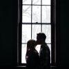 man and woman kissing beside window